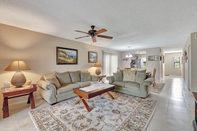 living room with a textured ceiling, ceiling fan, and light tile patterned floors