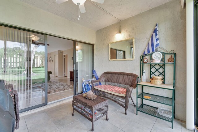 living area with tile patterned flooring, a ceiling fan, and a textured wall