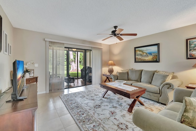 living area with light tile patterned floors, baseboards, a ceiling fan, and a textured ceiling