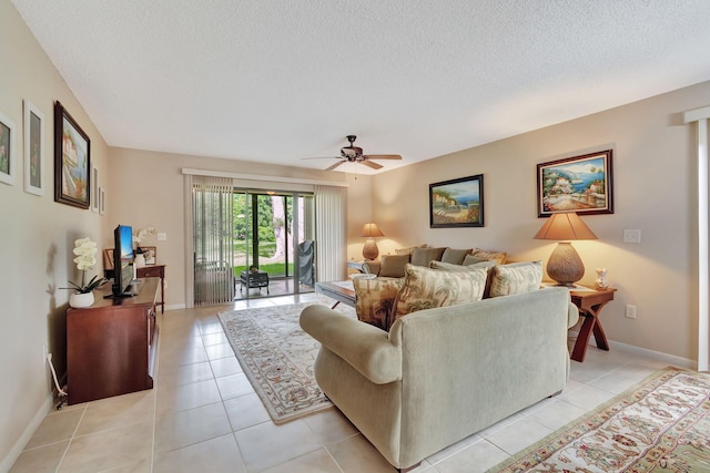 living room with a ceiling fan, a textured ceiling, baseboards, and light tile patterned floors