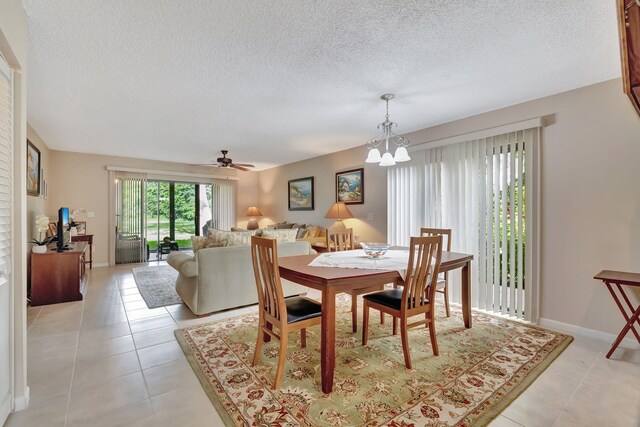 tiled dining area with a textured ceiling and ceiling fan with notable chandelier