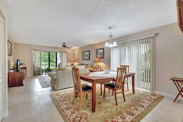 dining space featuring light tile patterned flooring, a textured ceiling, baseboards, and ceiling fan with notable chandelier