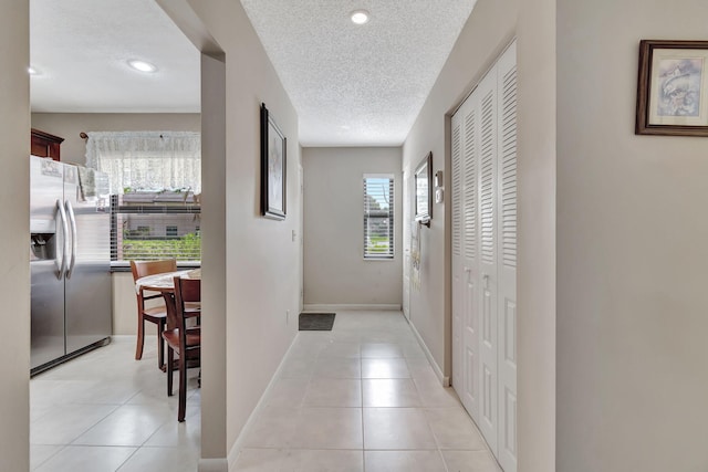 hallway with light tile patterned floors, baseboards, a textured ceiling, and recessed lighting