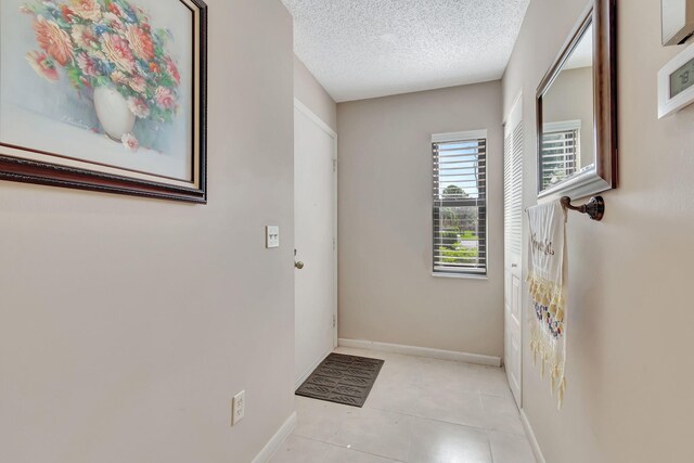 doorway with light tile patterned flooring and a textured ceiling