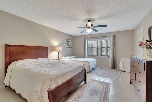 bedroom featuring ceiling fan, light tile patterned floors, and a textured ceiling