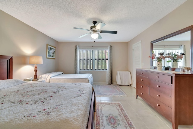 tiled bedroom featuring a closet, multiple windows, a textured ceiling, and ceiling fan