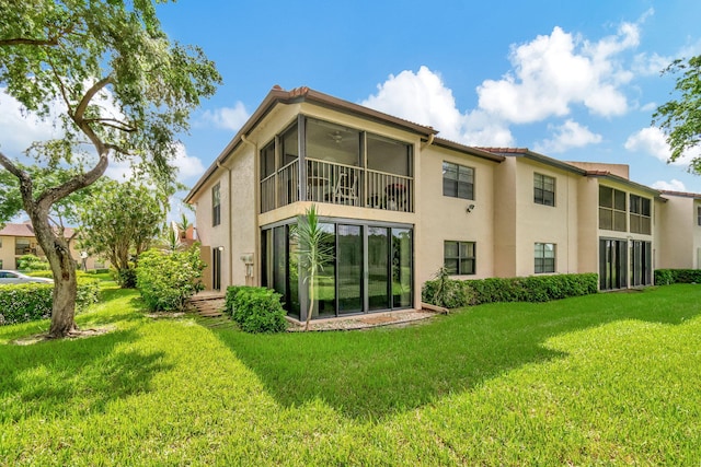 rear view of property featuring a sunroom and a lawn