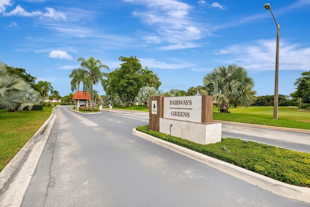 view of road featuring street lights, a gated entry, and curbs