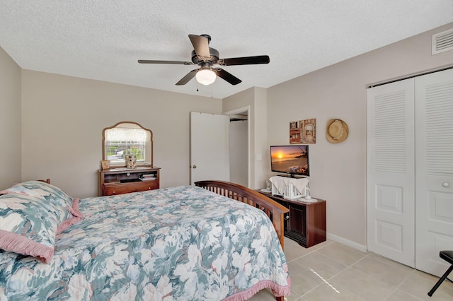 tiled bedroom featuring a closet, a textured ceiling, and ceiling fan