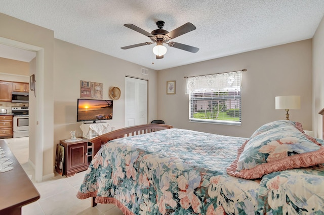 bedroom with a closet, a textured ceiling, light tile patterned floors, and ceiling fan