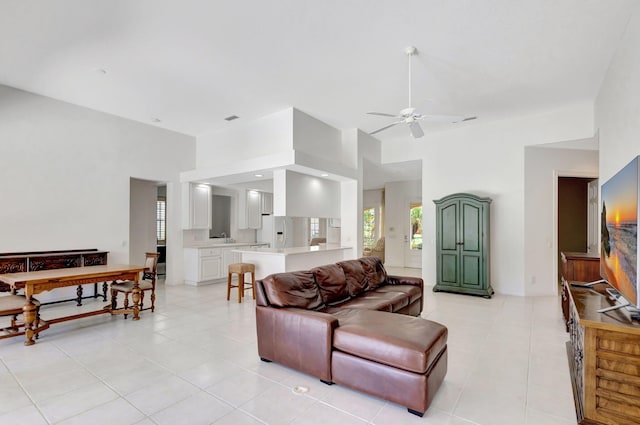 living room with a healthy amount of sunlight, a towering ceiling, ceiling fan, and light tile patterned floors