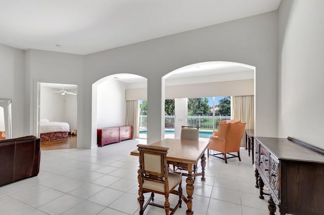 dining area featuring arched walkways, ceiling fan, and light tile patterned flooring