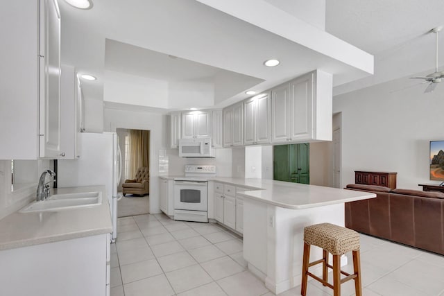 kitchen featuring sink, white cabinets, white appliances, and kitchen peninsula