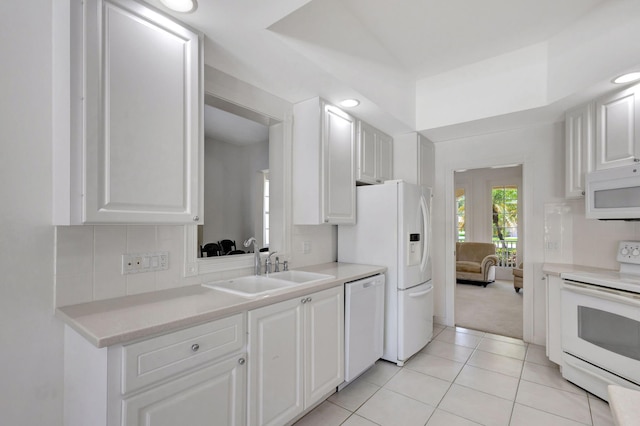 kitchen with tasteful backsplash, white cabinetry, light tile patterned floors, and white appliances