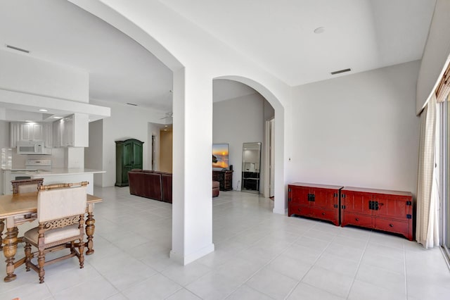 interior space with a ceiling fan, visible vents, arched walkways, and light tile patterned floors