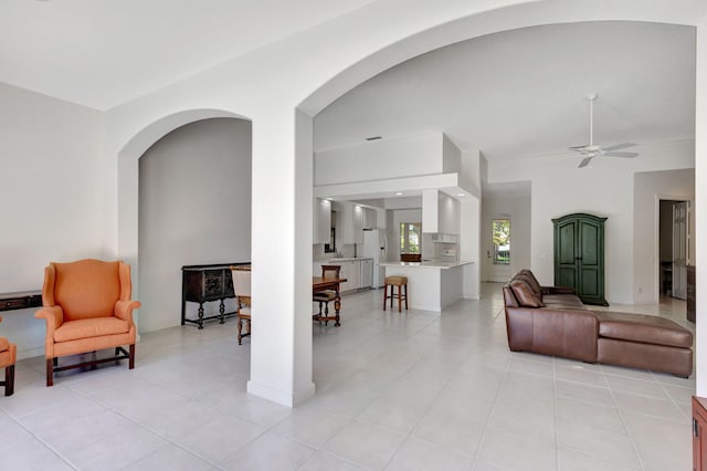 living room with arched walkways, ceiling fan, and light tile patterned floors