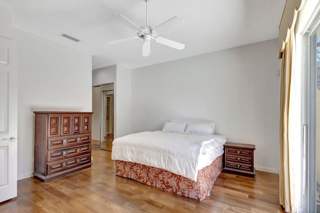 bedroom with wood finished floors, visible vents, a ceiling fan, and baseboards