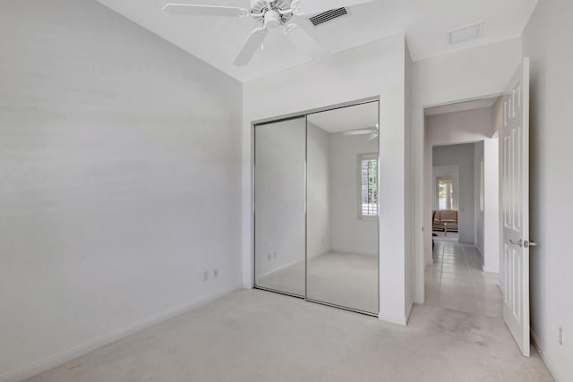 unfurnished bedroom with light carpet, a closet, and ceiling fan