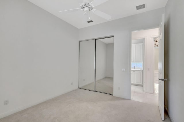 unfurnished bedroom featuring light carpet, a closet, and ceiling fan