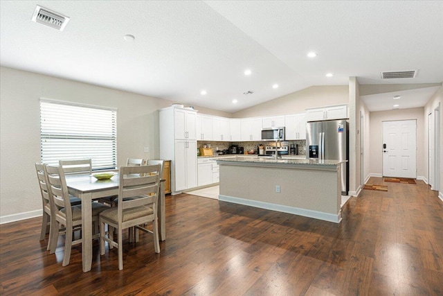 kitchen featuring white cabinets, a kitchen island with sink, dark hardwood / wood-style floors, appliances with stainless steel finishes, and decorative backsplash