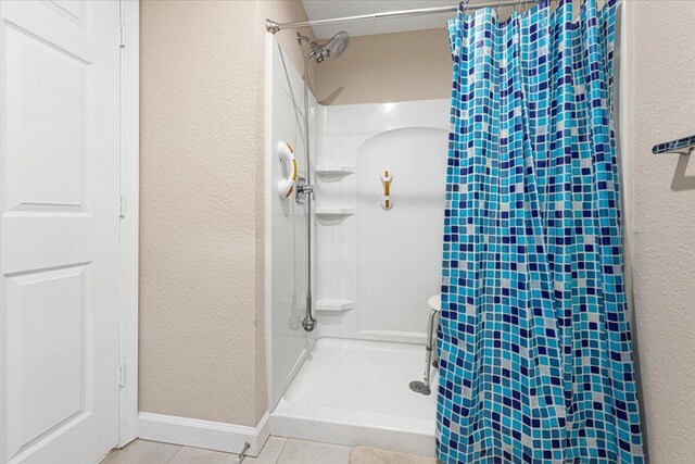 bathroom with a shower with shower curtain and tile patterned floors