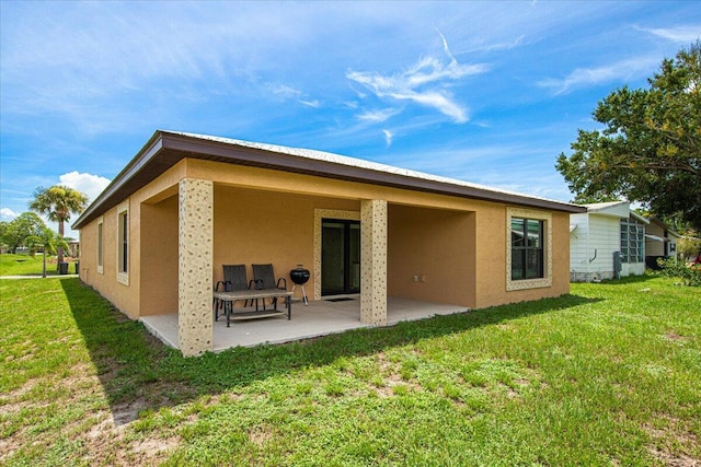 rear view of property featuring a patio and a lawn