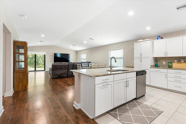 kitchen with lofted ceiling, stainless steel dishwasher, wood-type flooring, and white cabinets