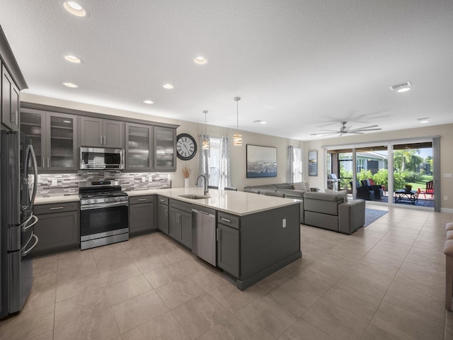 kitchen featuring sink, hanging light fixtures, appliances with stainless steel finishes, kitchen peninsula, and decorative backsplash