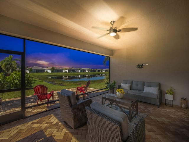 patio terrace at dusk featuring a water view, an outdoor hangout area, and ceiling fan