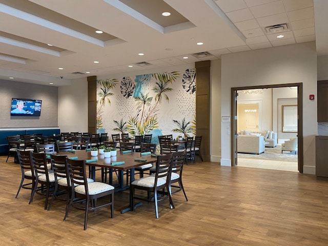 dining area with a paneled ceiling and light hardwood / wood-style floors