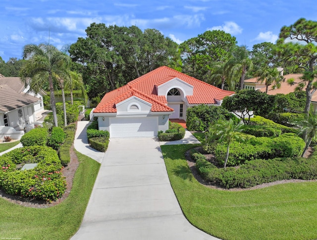 mediterranean / spanish house featuring a garage and a front lawn