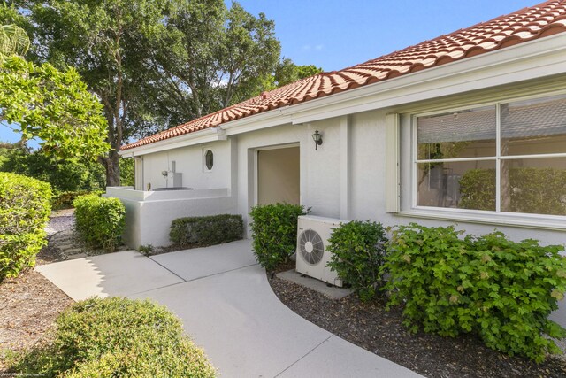 view of exterior entry with a patio and ac unit