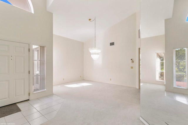 entrance foyer with high vaulted ceiling, a chandelier, and light carpet