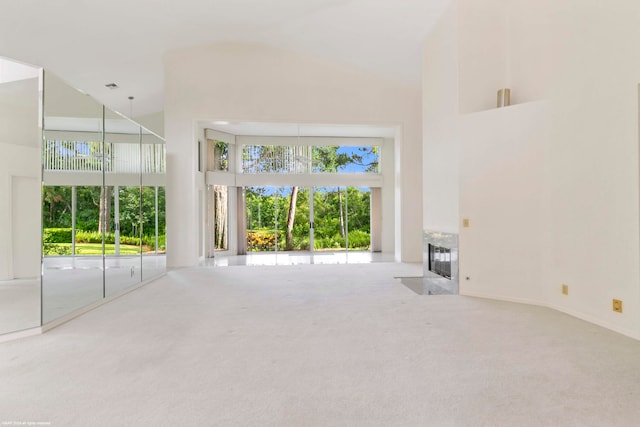 unfurnished living room featuring plenty of natural light, a high ceiling, and carpet flooring