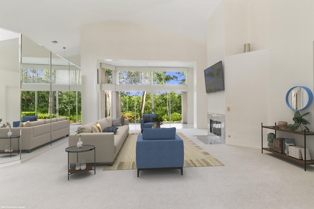 living room with a fireplace, a healthy amount of sunlight, carpet, and a high ceiling