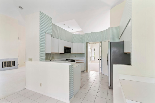 kitchen featuring range, white cabinetry, tasteful backsplash, refrigerator, and light colored carpet