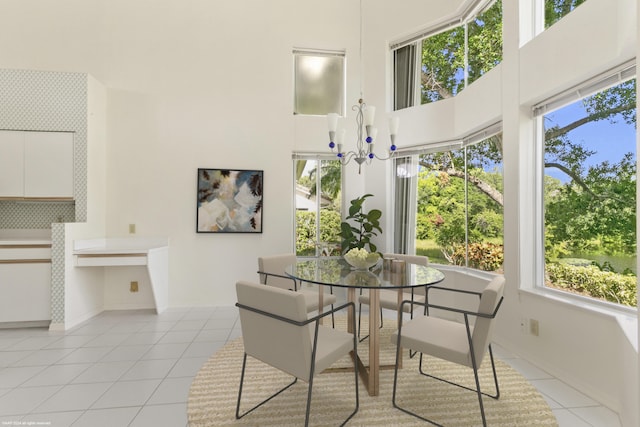 dining space with a towering ceiling, a notable chandelier, and light tile patterned floors