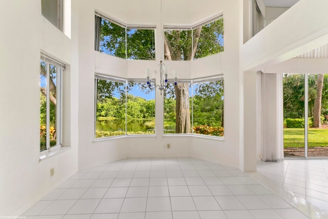 spare room featuring light tile patterned flooring, a notable chandelier, and a high ceiling