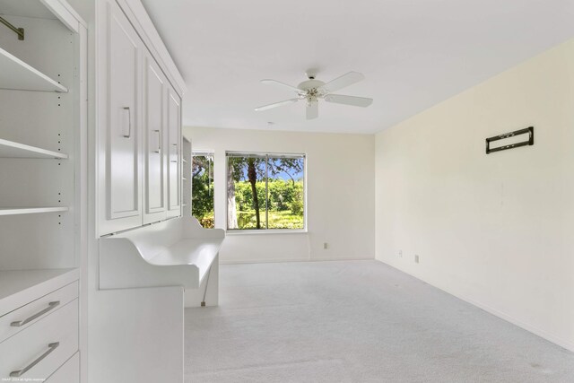 interior space with ceiling fan and light colored carpet