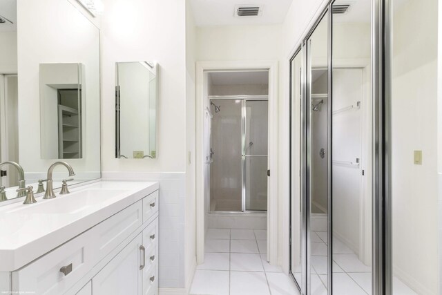 bathroom with a shower with shower door, vanity, and tile patterned floors