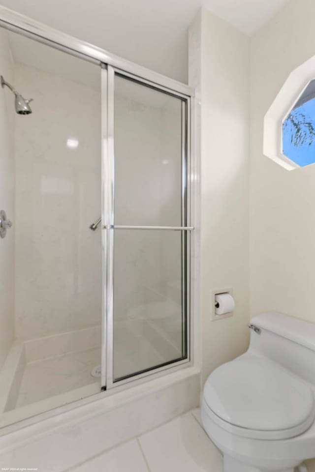 bathroom with toilet, tile patterned flooring, and walk in shower