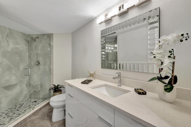 bathroom with tile patterned flooring, vanity, a shower with shower door, and toilet