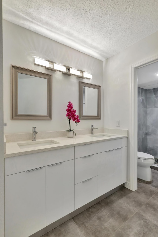 bathroom featuring vanity, a shower, a textured ceiling, and toilet