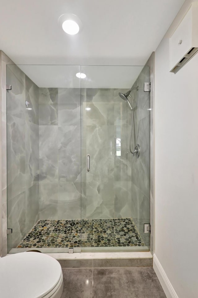 bathroom featuring a shower with door and toilet