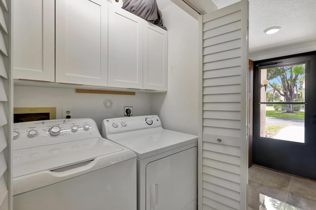 laundry area featuring independent washer and dryer, a wealth of natural light, cabinets, and a textured ceiling