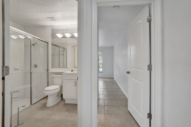 bathroom with vanity, toilet, a shower with door, tile patterned floors, and a textured ceiling