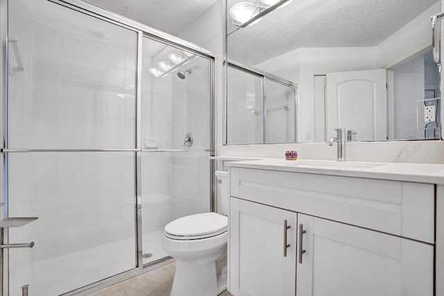 bathroom with vanity, a shower with door, toilet, and a textured ceiling