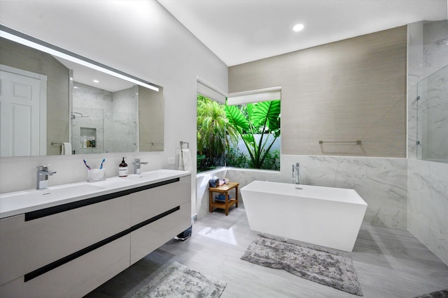 bathroom with independent shower and bath, vanity, and tile walls