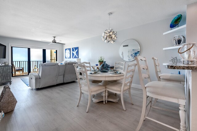 dining area featuring light wood-type flooring and ceiling fan with notable chandelier