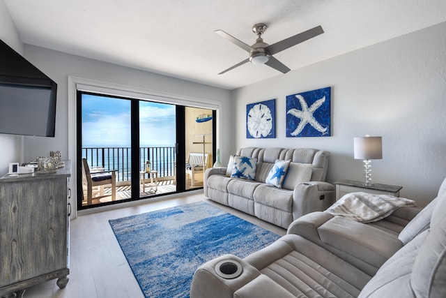 living room with light hardwood / wood-style floors, a water view, and ceiling fan